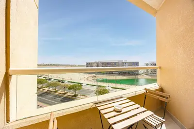 a balcony with a bench and a view of a beach at Chic 1BR Retreat with Lake Views & Modern Comforts in Dubai