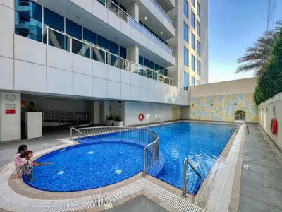 two children standing in front of a large swimming pool at Chic Marina Arcade Apartment Minutes to Beach in Dubai