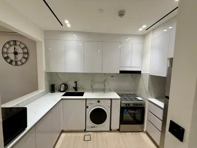 a kitchen with white cabinets and a washing machine at Smart & Stylish 1BHK With Keyless Entry! in Dubai