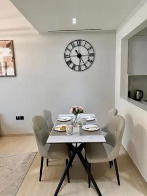 a dining room table with chairs and a clock on the wall at Smart & Stylish 1BHK With Keyless Entry! in Dubai