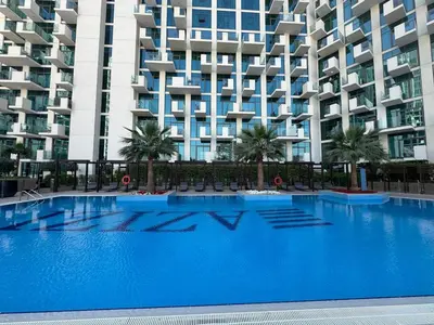 a large blue swimming pool in front of a building at Cozy studio Pet Friendly Pool, Gym, Water Near Downtown in Dubai