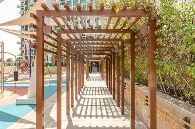 a wooden pergola over a pathway at a playground at Cozy studio Pet Friendly Pool, Gym, Water Near Downtown in Dubai