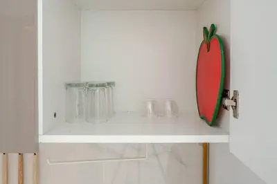 a white shelf with glasses and a board on it at Cozy studio Pet Friendly Pool, Gym, Water Near Downtown in Dubai