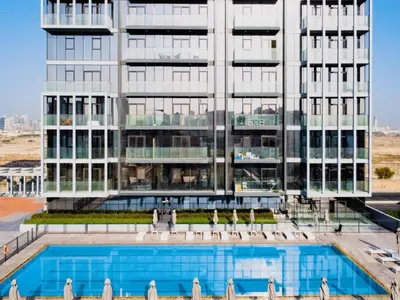 a large building with a swimming pool in front of it at Spacious JVC Studio Luxury Escape in Dubai
