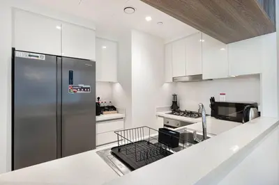 a kitchen with a stainless steel refrigerator and white cabinets at Mahogany 14 - 2BR Dubai Mall Walk & Burj Khalifa in Dubai