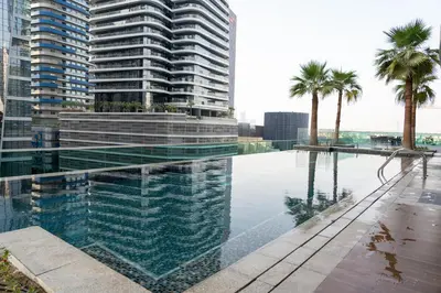 a swimming pool with palm trees and buildings at Nice 2 Bedroom Apartment! 5 Minutes walk to Dubai Mall, Downtown Dubai in Dubai