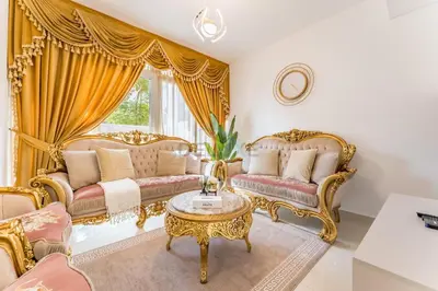 a living room with gold furniture and a table at Community and Pool View 3BR Townhouse, Minutes from Desert Camp,DAMAC Hills 2 Amargo by Deluxe Holiday Homes in Dubai