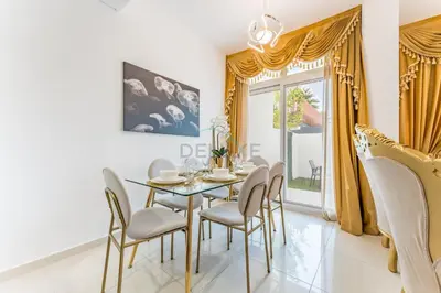 a dining room with a glass table and chairs at Community and Pool View 3BR Townhouse, Minutes from Desert Camp,DAMAC Hills 2 Amargo by Deluxe Holiday Homes in Dubai