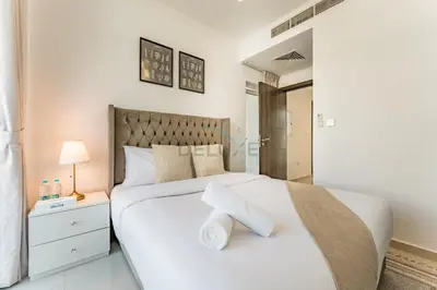 a bedroom with a large white bed and a lamp at Community and Pool View 3BR Townhouse, Minutes from Desert Camp,DAMAC Hills 2 Amargo by Deluxe Holiday Homes in Dubai