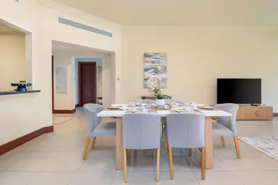 a dining room with a table with chairs and a television at Golden Mile at its Best 2BR Plus Maids Palm Jumeirah in Dubai