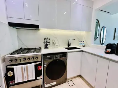 a white kitchen with a stove and a dishwasher at Comfortable 1br In Jvc Balcony Free Parking in Dubai