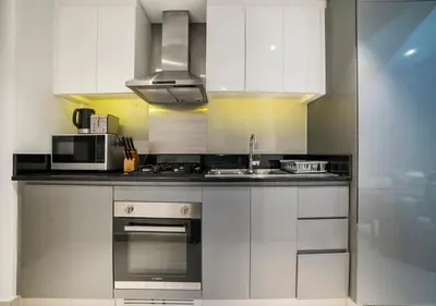 a kitchen with white cabinets and a sink and a microwave at Stunning Canal View with Balcony in Dubai