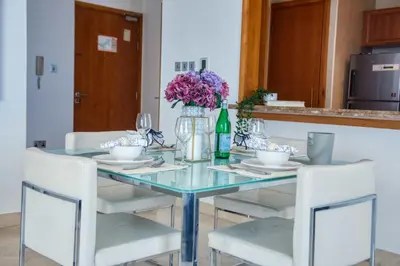 a dining room table with two chairs and a bottle of wine at The Smart Concierge - Dorra Bay in Dubai