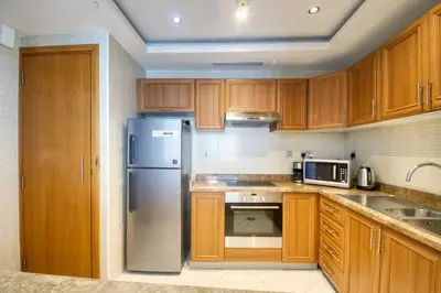 a kitchen with wooden cabinets and a stainless steel refrigerator at The Smart Concierge - Dorra Bay in Dubai