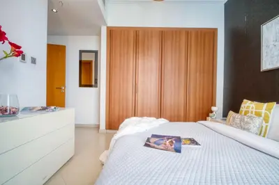 a bedroom with a white bed and a wooden cabinet at The Smart Concierge - Dorra Bay in Dubai