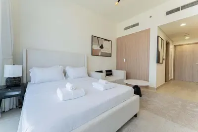 a bedroom with a large white bed with towels on it at TRPS - Azizi Riviera 23, Al Meydan - Contemporary Studio in the Heart of Dubai in Dubai