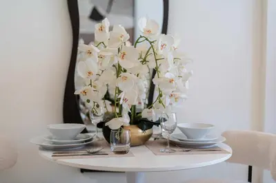 a table with a vase filled with white orchid flowers at TRPS - Azizi Riviera 23, Al Meydan - Contemporary Studio in the Heart of Dubai in Dubai