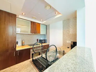a kitchen with a counter and two metal chairs at Vserve - 1 BR Escape in the Heart of Dubai Marina in Dubai