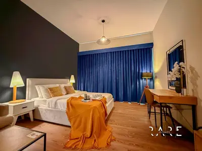 a bedroom with a bed and a table and a desk at Rare Holiday Homes - Mediterranean Cluster - Near Metro - Discovery Garden - Building# Med 83 - R105 in Dubai