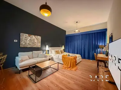 a living room with a couch and a table at Rare Holiday Homes - Mediterranean Cluster - Near Metro - Discovery Garden - Building# Med 83 - R105 in Dubai