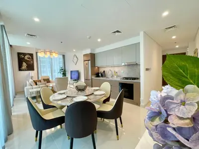 a kitchen and living room with a table and chairs at Elegant & Luxurious 1BR Apartment in Beach Isle in Dubai