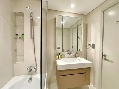 a white bathroom with a shower and a sink at Elegant & Luxurious 1BR Apartment in Beach Isle in Dubai