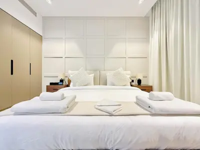 a large white bed with two white towels on it at Vserve - 1 BR Escape With City Views & Canal Vibes in Dubai