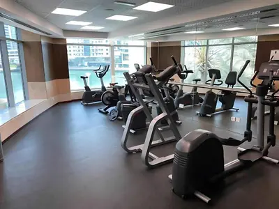 a gym with rows of treadmills and elliptical machines at Vserve - 1 BR Escape With City Views & Canal Vibes in Dubai