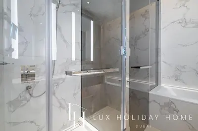 a bathroom with a shower with a glass door at LUX The Address Opera Downtown Suite in Dubai