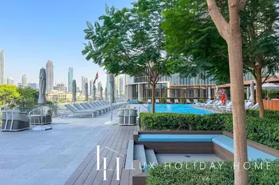 a park with benches and trees and a swimming pool at LUX The Address Opera Downtown Suite in Dubai