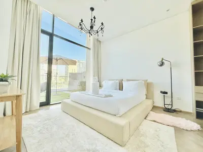 a white bedroom with a bed and a couch at Vserve -Elegant Penthouse Stay in the Heart of JVC in Dubai