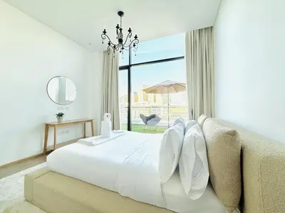 a white bedroom with a bed and a large window at Vserve -Elegant Penthouse Stay in the Heart of JVC in Dubai