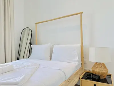 a bedroom with a bed with white sheets and a lamp at Vserve -Elegant Penthouse Stay in the Heart of JVC in Dubai