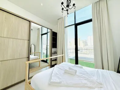 a bedroom with a bed and a large window at Vserve -Elegant Penthouse Stay in the Heart of JVC in Dubai