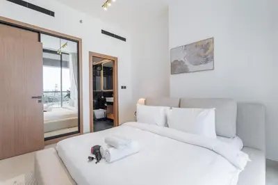 a bedroom with a large white bed with towels on it at Golden Stays - Binghatti Onyx I Brand New 1BR I Modern and Fully Furnished in Dubai