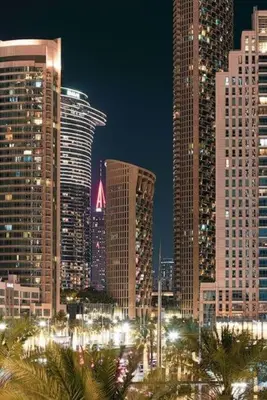a city skyline with tall buildings and palm trees at night at Luxurious Crown - Downtown - Fountains View in Dubai