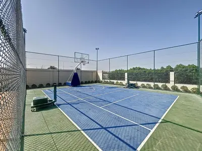 a tennis court with a net and a basketball hoop at Elegant - Three Bed Villa in Jumeirah Golf Estate in Dubai