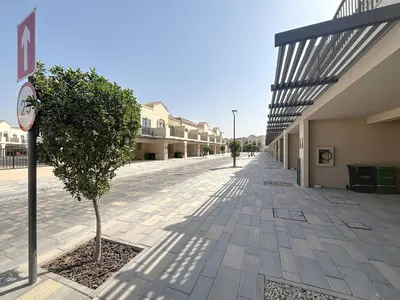 a tree on a sidewalk next to a building at Elegant - Three Bed Villa in Jumeirah Golf Estate in Dubai