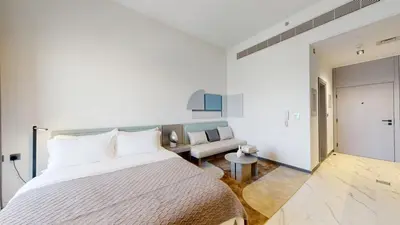 a white bedroom with a bed and a couch at Mag Eye 920 - Spacious Studio in Meydan in Dubai