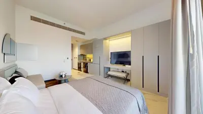 a bedroom with a white bed and a television at Mag Eye 920 - Spacious Studio in Meydan in Dubai