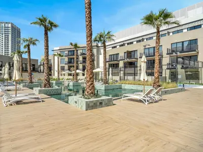 a courtyard with chairs and palm trees in front of a building at Brand New Luxury Apartment in JVC with Padel Court in Dubai