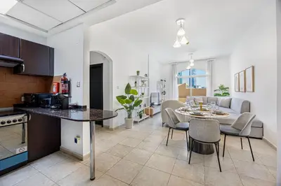 a kitchen and living room with a table and chairs at Luxury 2BR Haven with Expansive Terrace and Elegance in Dubai