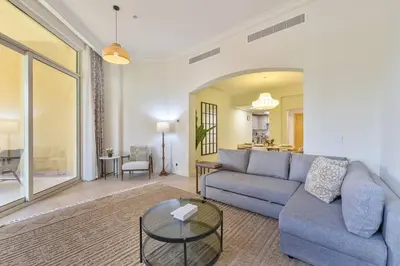 a living room with a blue couch and a glass table at Breathtaking 1BR Sea-View Palm Apt Beach & Pool in Dubai
