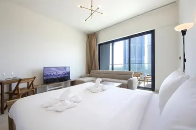 a white bedroom with a large bed and a living room at Modern Studio Stay in Business Bay Near Dubai Mall in Dubai