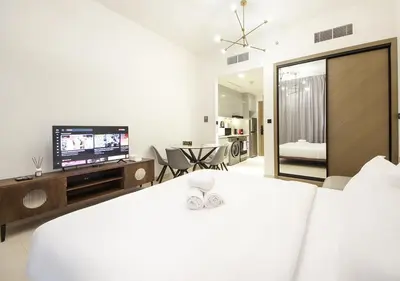 a white bedroom with a bed and a television at Elegant Studio in Binghatti Canal Near Dubai Mall in Dubai