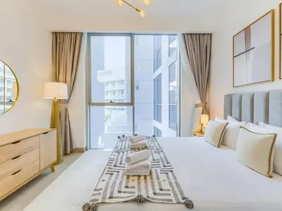 a bedroom with a white bed with a large window at TRPS - Luma 22, Jumeirah Village Circle - Chic 1BR Modern Sanctuary in Dubai