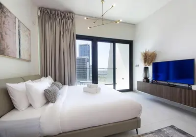 a bedroom with a large white bed and a large window at Chic Studio Apartment Binghatti Canal Business Bay in Dubai