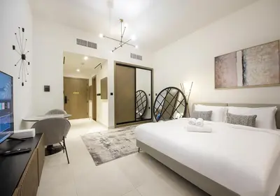 a bedroom with a large white bed and a desk at Chic Studio Apartment Binghatti Canal Business Bay in Dubai