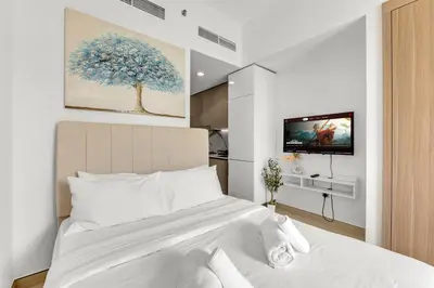 a bedroom with a white bed and a tv at Amazing Studio in Azizi Riviera 1 in Dubai