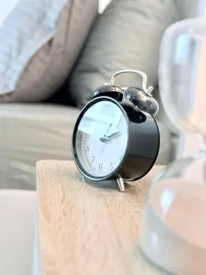 a black alarm clock sitting on top of a table at LivWithUs-Studio in One BR Setup, Dubai Marina in Dubai